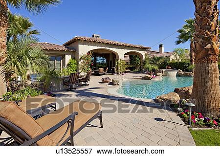 Stock Photo - Outdoors seating furniture near swimming pool in luxury villa. Fotosearch