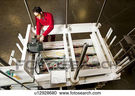 Stock Image - Overhead view of technician repairing motor on electrical circuit. Fotosearch