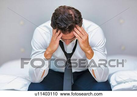 Overworked and stressed businessman sitting on the bed View Large Photo Image Stock Image - Overworked and stressed businessman sitting on the bed. Fotosearch