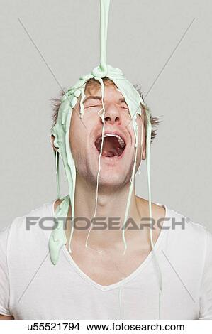 Picture - Paint falling on young Caucasian man against gray background. Fotosearch