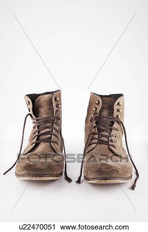 Stock Image - Pair of brown boots with untied laces over white background. Fotosearch