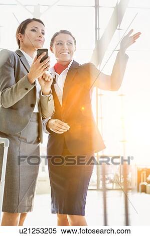 Stock Photography - Passenger service agent assisting and giving directions with businesswoman in airport. Fotosearch