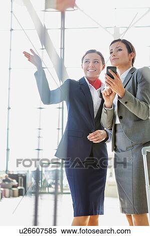 Stock Photography - Passenger service agent assisting and giving directions with businesswoman in airport. Fotosearch