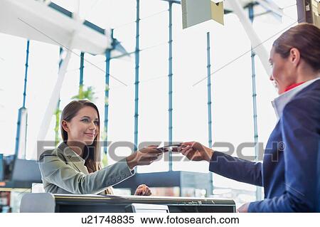 Passenger service agent giving boarding pass to young attractive businesswoman after check in at airport View Large Photo Image Stock Photography - Passenger service agent giving boarding pass to young attractive businesswoman after check in at airport. Fotosearch