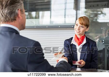 Passenger service agent giving businessman passport and boarding pass in check in area at airport View Large Photo Image Stock Photo - Passenger service agent giving businessman passport and boarding pass in check in area at airport. Fotosearch