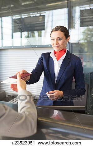 Passenger service agent giving woman's passport and boarding pass in check in area at airport View Large Photo Image Stock Image - Passenger service agent giving woman's passport and boarding pass in check in area at airport. Fotosearch