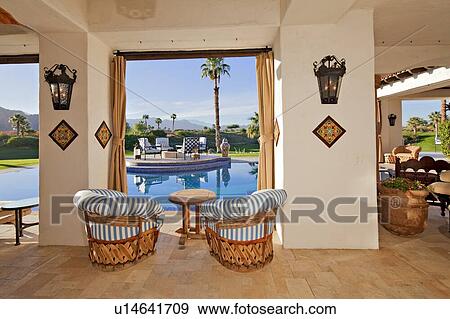 Stock Photo - Patio with seating furniture at poolside in mansion. Fotosearch
