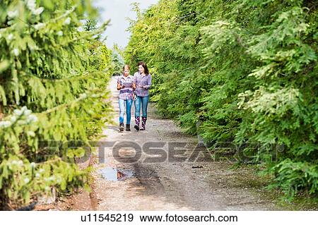 Stock Photo - Photo of mature woman writing report on clipboard while walking with coworker in greenhouse. Fotosearch