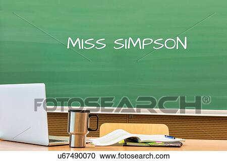 Stock Image - Photo of professor desk in classroom with Miss Simpson name written in black board. Fotosearch