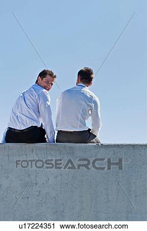 Photo of thoughtful businessmen sitting and relaxing on rooftop View Large Photo Image Stock Image - Photo of thoughtful businessmen sitting and relaxing on rooftop . Fotosearch