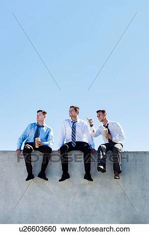 Stock Image - Photo of thoughtful businessmen sitting and relaxing on rooftop . Fotosearch