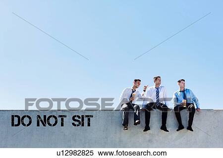 Stock Photography - Photo of thoughtful businessmen sitting and relaxing on rooftop during break in office. Fotosearch