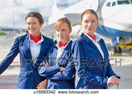 Photo of three confident flight attendants standing against airplane in airport View Large Photo Image Stock Image - Photo of three confident flight attendants standing against airplane in airport. Fotosearch