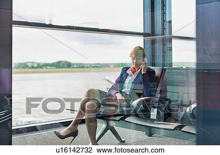 Photo of young attractive airport staff sitting while talking on smartphone View Large Photo Image Stock Image - Photo of young attractive airport staff sitting while talking on smartphone . Fotosearch