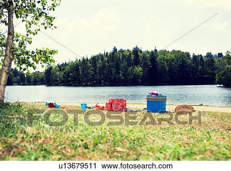 Stock Image - Picnic gear on lakeshore. Fotosearch
