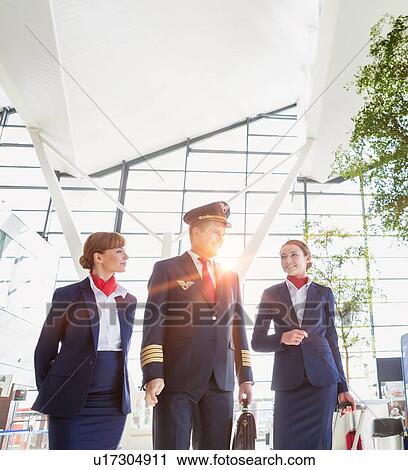 Stock Image - Pilot with flight attendants walking in the airport. Fotosearch
