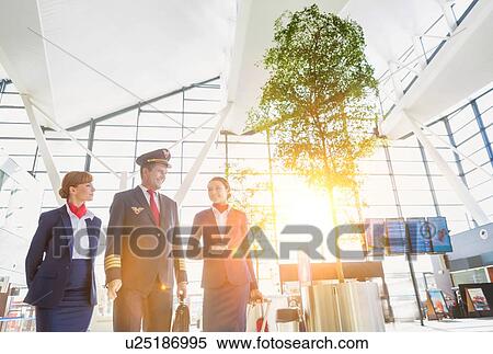 Stock Photography - Pilot with flight attendants walking in the airport. Fotosearch