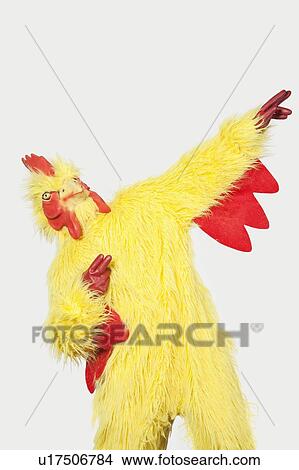 Playful young man in chicken suit against gray background View Large Photo Image Picture - Playful young man in chicken suit against gray background. Fotosearch