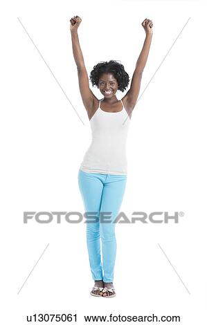 Stock Image - Portrait of a cheerful young woman with arms raised standing over white background. Fotosearch