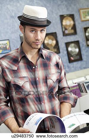Stock Image - Portrait of a confident music store owner with book. Fotosearch