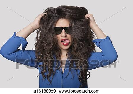 Stock Photo - Portrait of a flirtatious young woman over gray background. Fotosearch