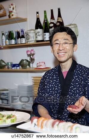 Portrait of a happy Asian chef holding fish meat in restaurant View Large Photo Image Stock Photo - Portrait of a happy Asian chef holding fish meat in restaurant. Fotosearch