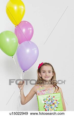 Portrait of a happy girl with party balloons and gift over colored background View Large Photo Image Stock Photo - Portrait of a happy girl with party balloons and gift over colored background. Fotosearch