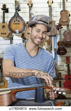 Portrait of a happy owner of music store restringing guitar View Large Photo Image Stock Photography - Portrait of a happy owner of music store restringing guitar. Fotosearch