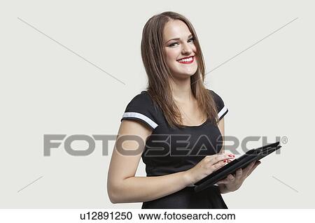 Portrait of a happy woman using tablet PC over gray background View Large Photo Image Stock Image - Portrait of a happy woman using tablet PC over gray background. Fotosearch