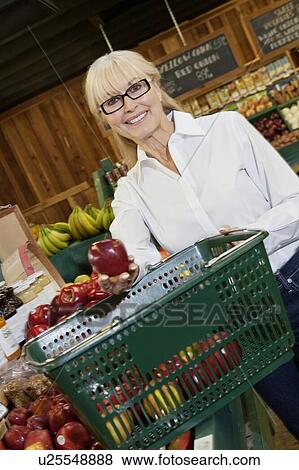 Stock Photo - Portrait of a senior woman fresh apples in basket. Fotosearch