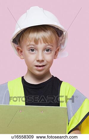 Stock Photo - Portrait of a young boy pretending at construction worker over pink background. Fotosearch