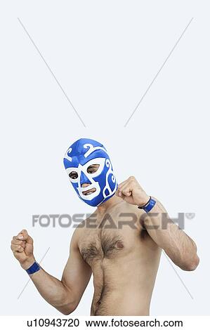 Stock Image - Portrait of a young male wrestler celebrating victory against gray background. Fotosearch