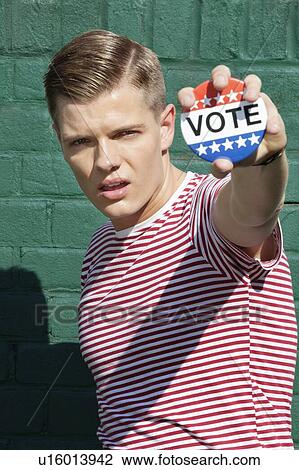 Portrait of a young man holding vote badge View Large Photo Image Stock Image - Portrait of a young man holding vote badge. Fotosearch