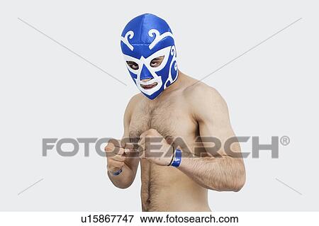 Stock Photo - Portrait of a young shirtless male wrestler wearing wrestling mask over gray background. Fotosearch
