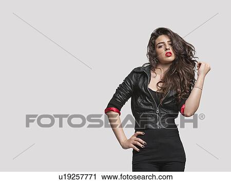 Portrait of a young woman in stylish outfit standing over gray background View Large Photo Image Stock Image - Portrait of a young woman in stylish outfit standing over gray background. Fotosearch