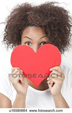 Picture - Portrait of African American young woman peeking over heart shape. Fotosearch