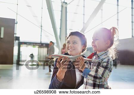Portrait of airport staff holding airplane toy while playing with cute little girl in airport View Large Photo Image Stock Photo - Portrait of airport staff holding airplane toy while playing with cute little girl in airport. Fotosearch