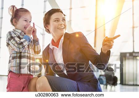 Stock Image - Portrait of airport staff playing with cute little girl in airport. Fotosearch