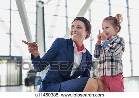 Stock Photography - Portrait of airport staff playing with cute little girl in airport. Fotosearch