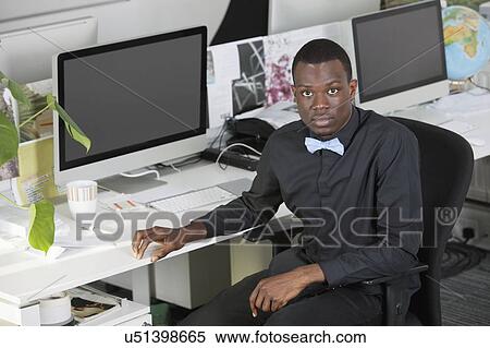 Stock Photography - Portrait of an African American businessman sitting at desk in office. Fotosearch