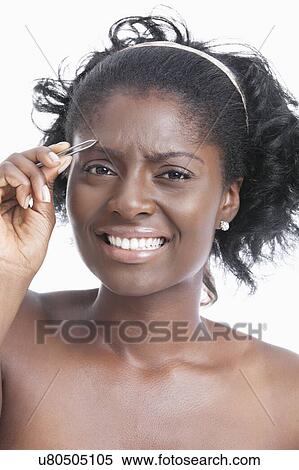 Portrait of an African American young woman tweezing her eyebrows View Large Photo Image Stock Photography - Portrait of an African American young woman tweezing her eyebrows. Fotosearch