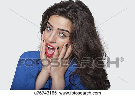 Stock Photography - Portrait of an amazed young woman over gray background. Fotosearch