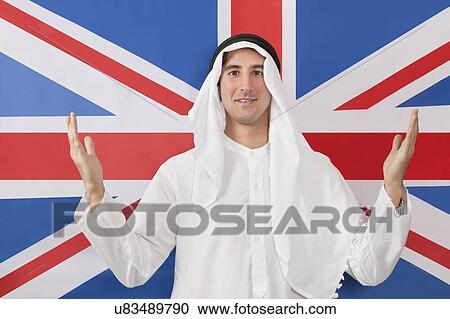 Stock Image - Portrait of an Arab man in traditional clothes against American flag. Fotosearch