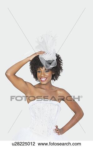 Stock Image - Portrait of an attractive African American bride wearing feather fascinator over gray background. Fotosearch