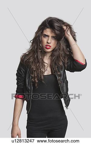 Portrait of an irritated young woman standing against gray background View Large Photo Image Stock Photo - Portrait of an irritated young woman standing against gray background. Fotosearch