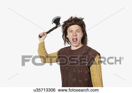 Portrait of angry young man in caveman costume holding axe against gray background View Large Photo Image Stock Photograph - Portrait of angry young man in caveman costume holding axe against gray background. Fotosearch