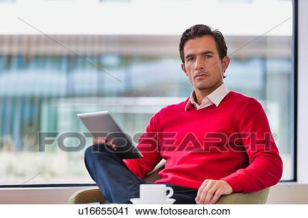 Portrait of attractive businessman using digital tablet while sitting and drinking coffee in lobby View Large Photo Image Stock Image - Portrait of attractive businessman using digital tablet while sitting and drinking coffee in lobby. Fotosearch