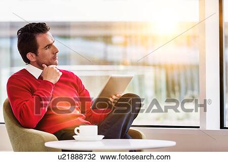Portrait of attractive businessman using digital tablet while sitting and drinking coffee in lobby View Large Photo Image Stock Image - Portrait of attractive businessman using digital tablet while sitting and drinking coffee in lobby. Fotosearch