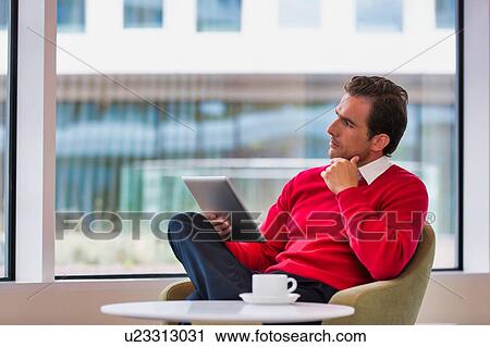 Portrait of attractive businessman using digital tablet while sitting and drinking coffee in lobby View Large Photo Image Stock Image - Portrait of attractive businessman using digital tablet while sitting and drinking coffee in lobby. Fotosearch