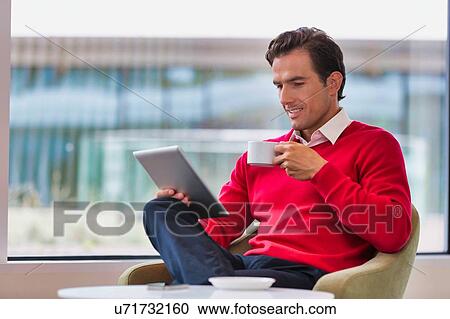 Portrait of attractive businessman using digital tablet while sitting and drinking coffee in lobby View Large Photo Image Stock Image - Portrait of attractive businessman using digital tablet while sitting and drinking coffee in lobby. Fotosearch
